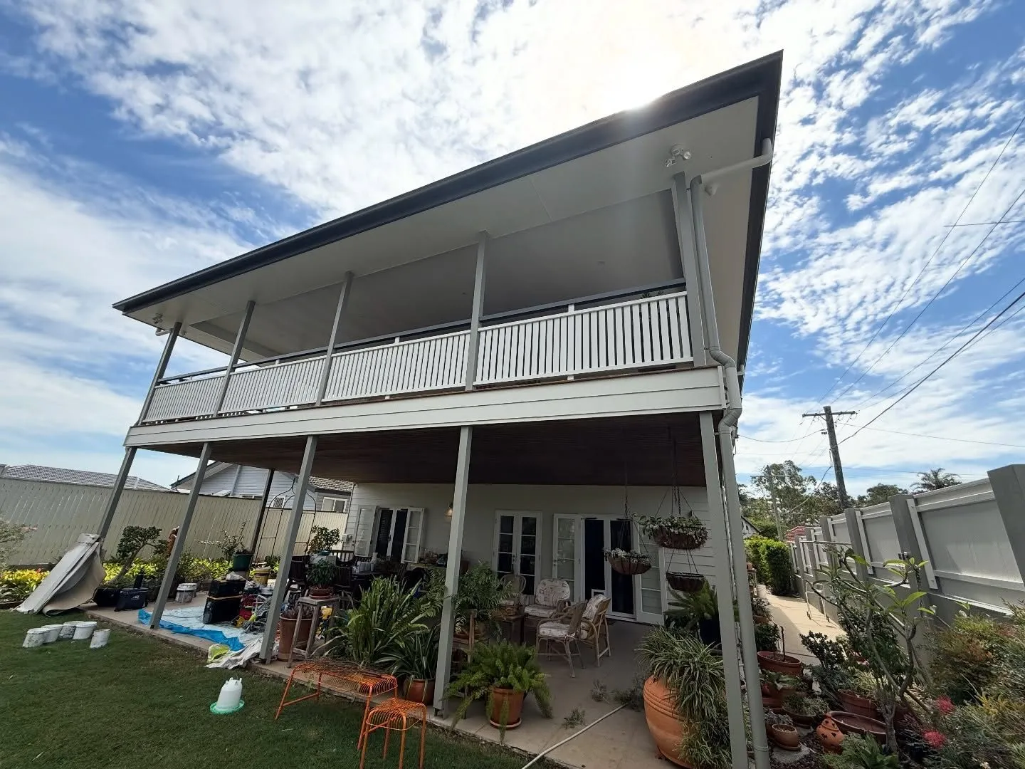 Highset Queenslander in Stafford repainted white with grey trims, verandah balustrades and window hoods